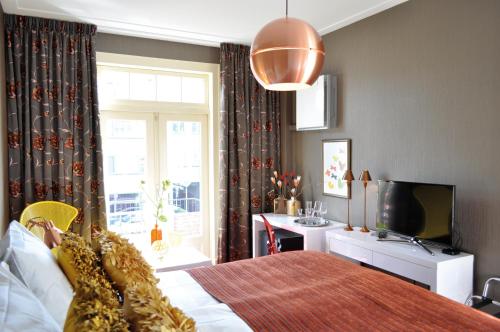 a bedroom with a bed and a tv and a window at City Hotel Koningsvlinder in Veenendaal