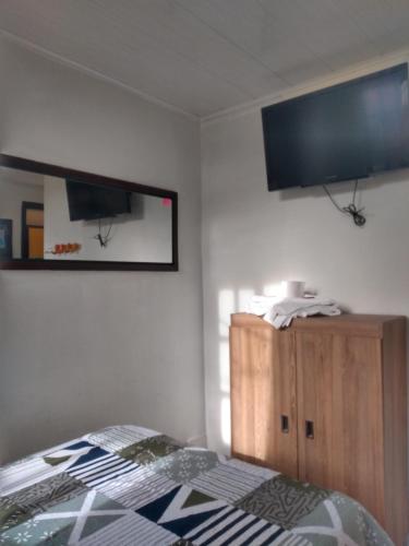 a bedroom with a bed and a tv on the wall at Hostal VIYAJE in Funza