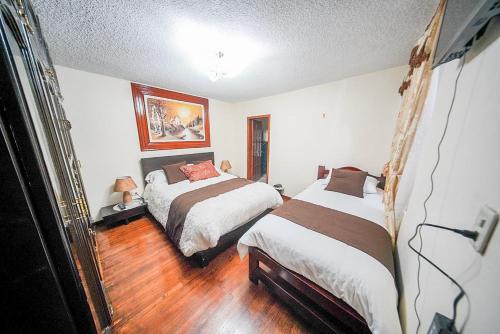 a bedroom with two beds and a wooden floor at Casa de Mármol in Riobamba