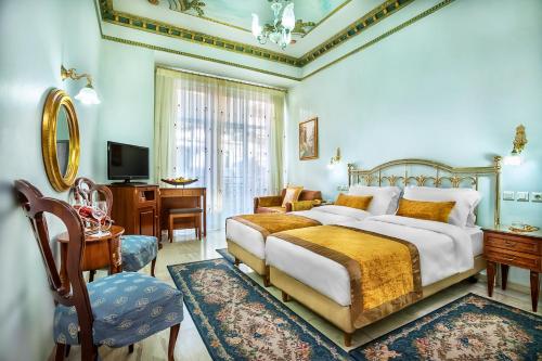 um quarto com uma cama, uma secretária e uma televisão em Imperial Palace Classical Hotel Thessaloniki em Tessalônica