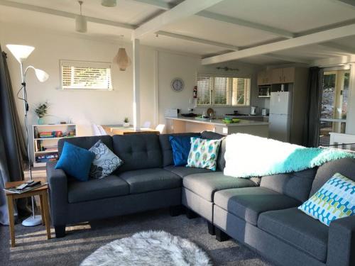 een woonkamer met een grijze bank en blauwe kussens bij 9 Alpine Avenue in Hanmer Springs