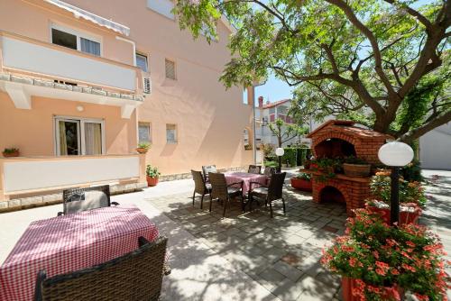 a patio with a table and chairs and a fireplace at Apartments Mar - 150 m from sea in Rab