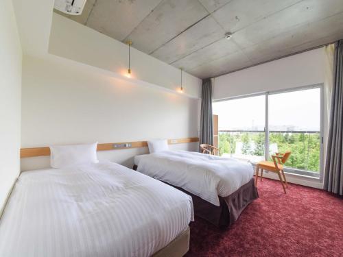 a hotel room with two beds and a large window at The Day Osaka in Osaka