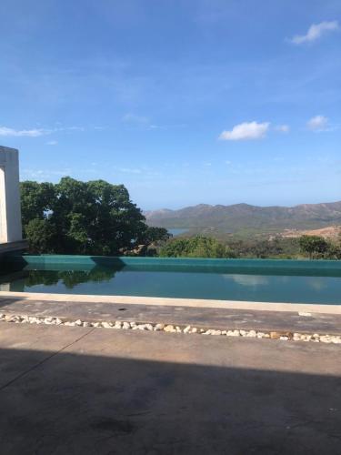 a pool of water with mountains in the background at Villa Californienne proche Nouméa in Païta