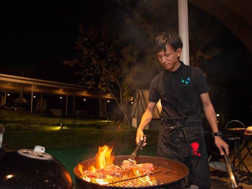 a man is cooking meat on a grill at The Day Osaka in Osaka