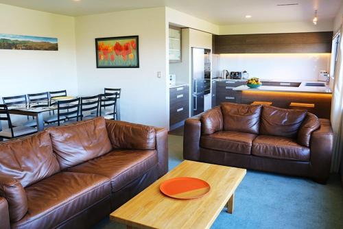 a living room with two leather couches and a kitchen at 12 Oregon Heights in Hanmer Springs