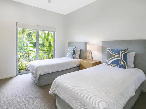 Dos camas en una habitación con ventana. en Go with the flow, Noosa Sound, en Noosa Heads