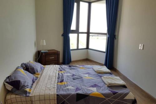 a bedroom with a bed with blue curtains and a window at 1504 Ha Long in Ha Long