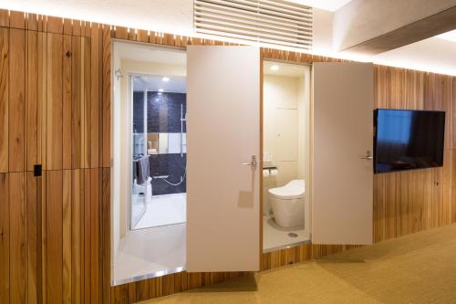 a bathroom with a toilet and a television on a wall at Sakura Cross Hotel Tokyo Kayabacho in Tokyo