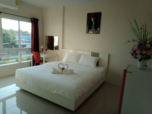 a bedroom with a white bed with a bow on it at เคทู เกสเฮาส์ (K2 Guesthouse) in Chon Buri