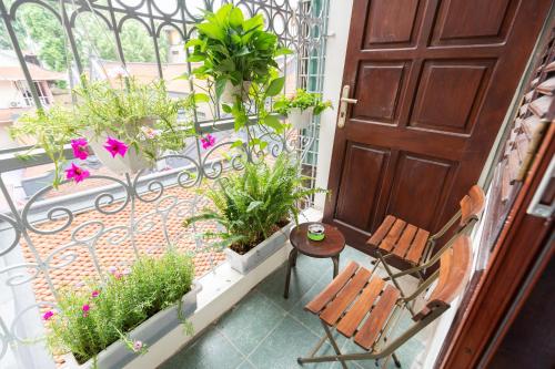 a balcony with a door and two chairs and plants at Nusmile's Hostel and Travel in Hanoi