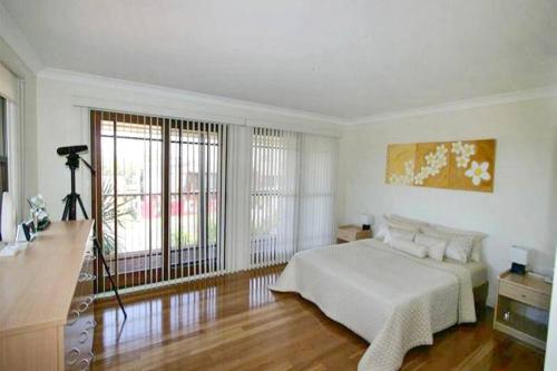 a white bedroom with a bed and a large window at Illalangi - views, pool, walk to beach in North Haven