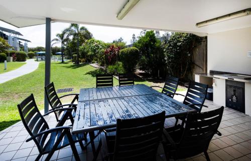a wooden table and chairs on a patio at Pacific Marina Apartments in Coffs Harbour