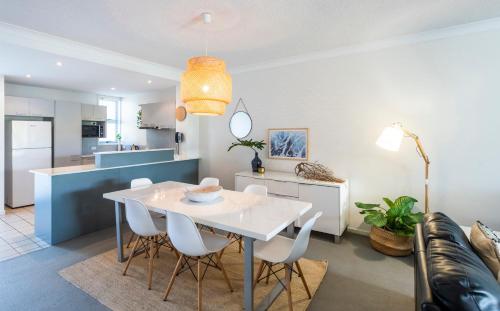 a dining room and kitchen with a white table and chairs at Pacific Marina Apartments in Coffs Harbour