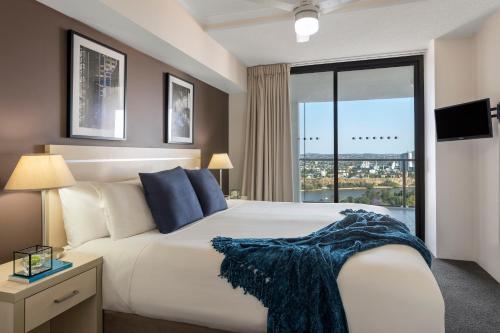 een slaapkamer met een groot bed en een groot raam bij Oaks Brisbane River City Suites in Brisbane