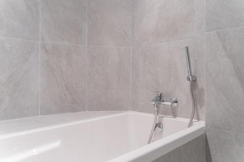 a white bath tub with a shower in a bathroom at True Siam Phayathai Hotel in Bangkok