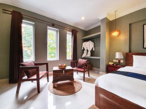 um quarto com uma cama, uma cadeira e uma mesa em Plumeria Hotel & Spa em Siem Reap