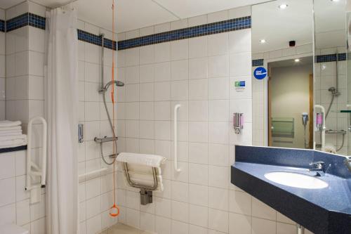 een badkamer met een wastafel en een douche bij Holiday Inn Express Portsmouth Gunwharf Quays, an IHG Hotel in Portsmouth