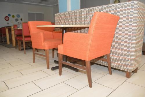 een rij oranje stoelen en een tafel in een restaurant bij Holiday Inn Express San Angelo by IHG in San Angelo