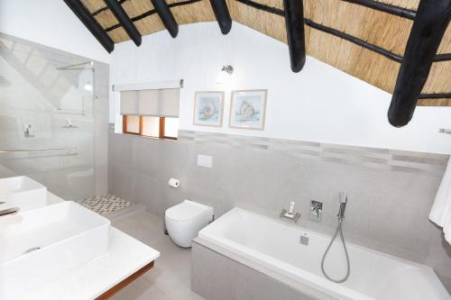 La salle de bains blanche est pourvue d'un lavabo et de toilettes. dans l'établissement Kruger Park Lodge Unit No. 610A, à Hazyview