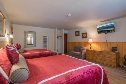 a bedroom with two beds and a chair and a television at Black Forest Lodge in Big Bear Lake