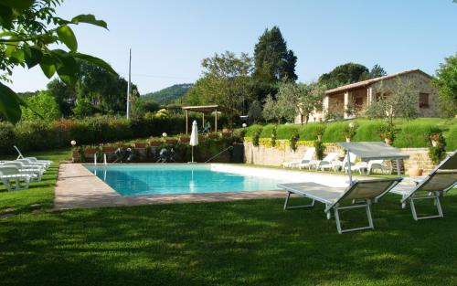 a swimming pool in a yard with chairs and a house at Agriturismo Nobile in Montepulciano