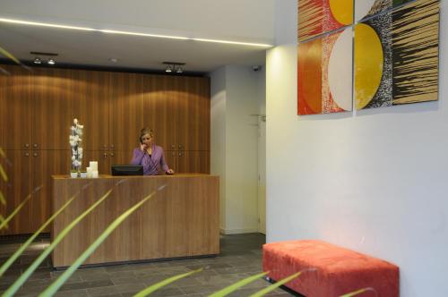 a woman talking on a phone at a reception desk at Hotel Corbie Lommel in Lommel