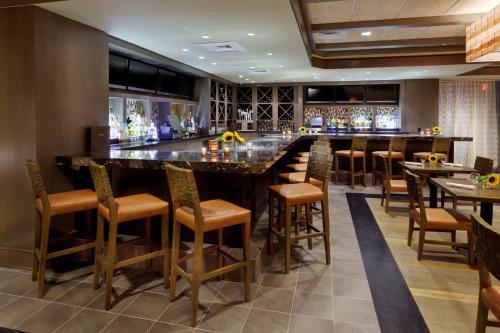 a bar in a restaurant with wooden stools at Hotel Indigo East End by IHG in Riverhead