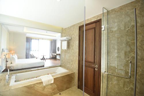 a bathroom with a shower and a sink and a mirror at Phu Cuong Hotel Ca Mau in Cà Mau