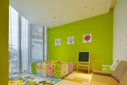 a room with a green wall with a chair and a crib at Holiday Inn Express Shanghai Jiading Industry Park by IHG in Jiading