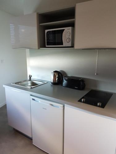 a kitchen with a sink and a microwave at All Suites Appart Hôtel - Bordeaux - Pessac in Pessac
