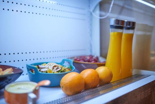 a kitchen counter with oranges and a salad and drinks at CityNote Hotel Shangxiajiu Pedestrian Guangzhou in Guangzhou