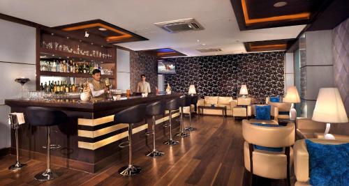 a bar in a restaurant with a man standing behind it at Country Inn & Suites by Radisson, Gurugram Sector 12 in Gurgaon