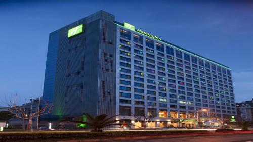 un grand bâtiment avec un panneau vert dans l'établissement Holiday Inn Shanghai Pudong Nanpu, an IHG Hotel, à Shanghai