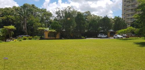 un patio verde con un edificio y coches al fondo en Bobato building, en Curepipe