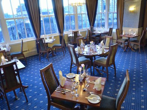 a dining room with tables and chairs and windows at The Riverside in Kendal