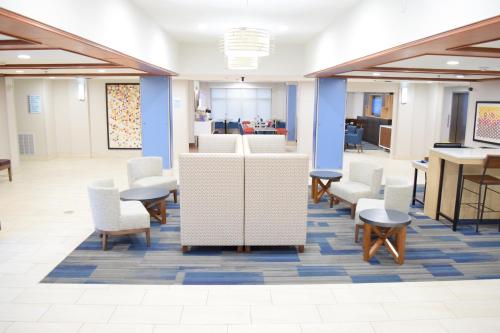 a lobby with white chairs and tables and a desk at Holiday Inn Express & Suites Pensacola West I-10 by IHG in Pensacola
