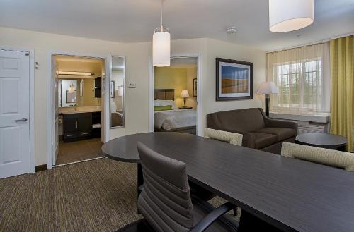 a living room with a dining room table and a bedroom at Candlewood Suites Louisville Airport by IHG in Louisville