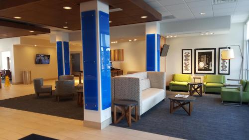 um átrio com um sofá, cadeiras e mesas em Holiday Inn Express & Suites Toledo West, an IHG Hotel em Toledo