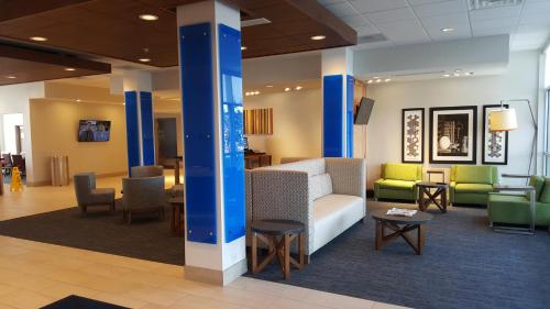 a lobby with a couch and chairs and tables at Holiday Inn Express & Suites Toledo West by IHG in Toledo