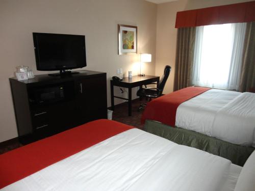 ein Hotelzimmer mit 2 Betten und einem Schreibtisch mit einem TV in der Unterkunft Holiday Inn Express Kenedy, an IHG Hotel in Kenedy