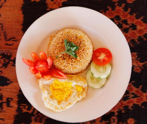 a plate of food with eggs and tomatoes on a table at Pavilla Labuan Bajo in Labuan Bajo
