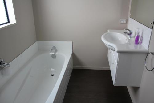 a white bathroom with a sink and a white bath tub at 3 Bellbird Place in Hanmer Springs