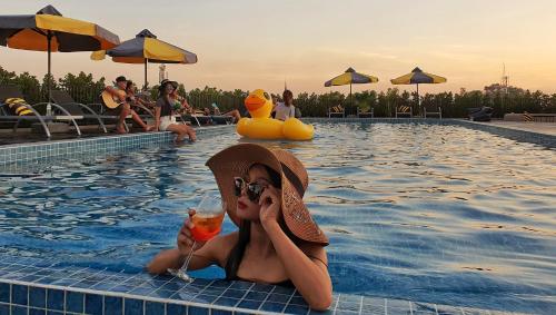 uma mulher numa piscina segurando uma bebida em The Twizt - Lifestyle Hostel & Hotel em Siem Reap