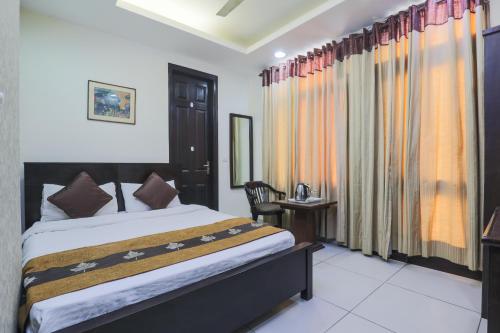 a bedroom with a bed and a table and a chair at The Hermitage by The Cosy Hotels Near Lotus Temple in New Delhi