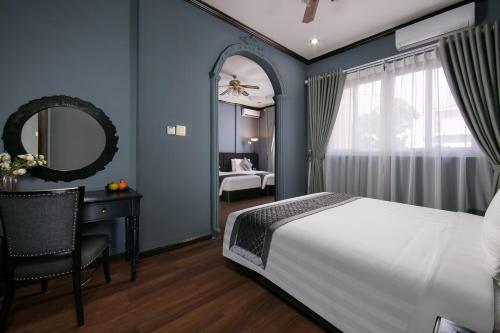 a bedroom with a bed and a desk and a mirror at Vientiane Boutique Hotel in Vientiane