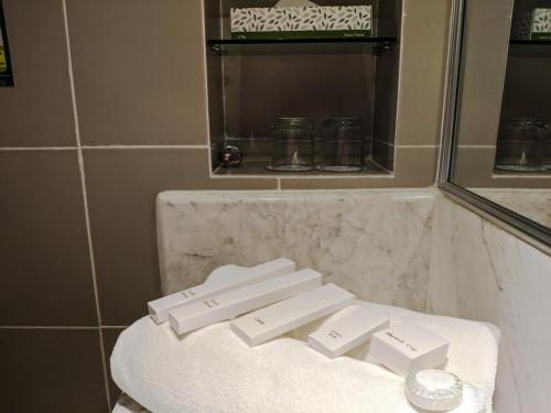 ein Badezimmer mit einem weißen Waschbecken und einem Spiegel in der Unterkunft Sabah Oriental Hotel in Kota Kinabalu