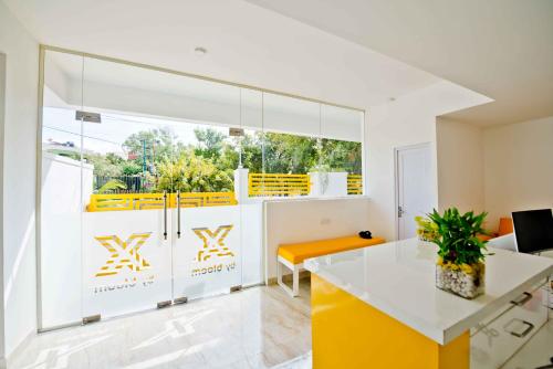 a kitchen with yellow and white cabinets and a table at X by Bloom I Hebbal Manyata Park in Bangalore