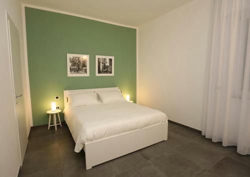 a bedroom with a white bed and a green wall at Delia Rooms & Gallery in Naples
