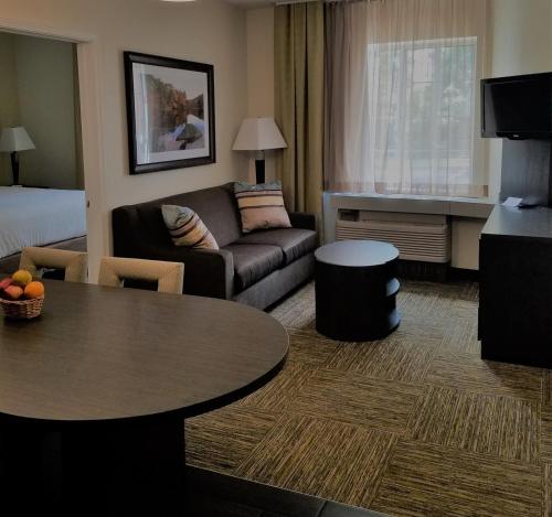 a living room with a couch and a table in a hotel room at Candlewood Suites - East Syracuse - Carrier Circle by IHG in East Syracuse